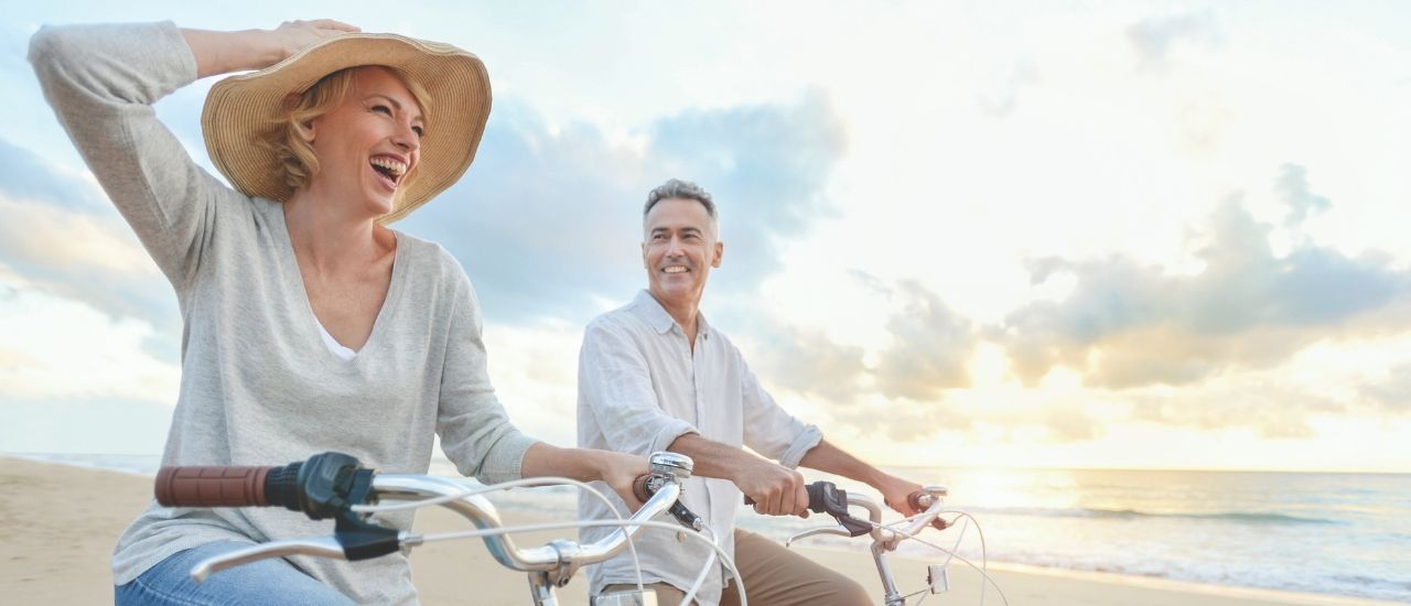 couple smiling riding on the beach minutes away from Bayso Sarasota